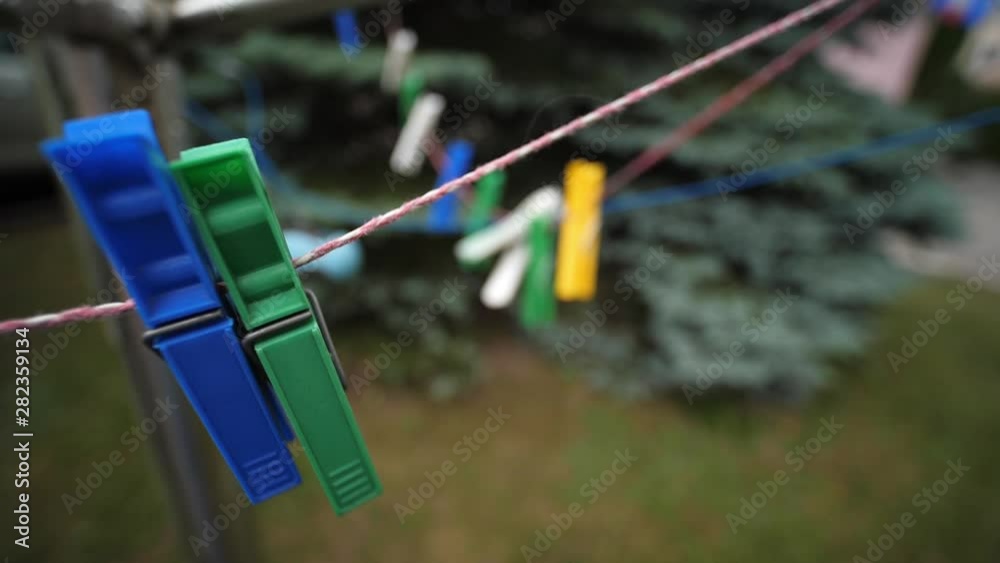 Colorful laundry Pegs clothes pins hanging on washing line outdoors. Windy day in Slow motion