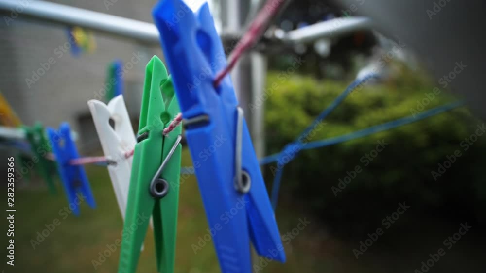 Colorful laundry Pegs clothes pins hanging on washing line outdoors. Windy day in Slow motion