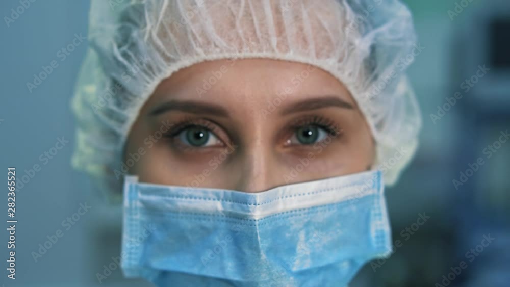Extra close-up of the eye tired assistant surgeon. She is in a mask looking at the camera, after surgery Extra close-up of the eye tired assistant surgeon. She is in a mask looking at the camera, after surgery