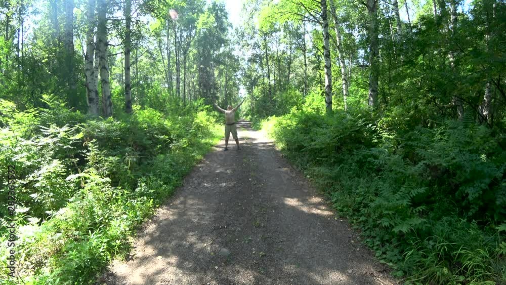 Middle-aged man in the forest. Raises his hands up and jumps up. Shirtless. In cargo shorts. Summer. Sunny. Middle-aged man in the forest. Raises his hands up and jumps up. Shirtless. In cargo shorts. Summer. Sunny.
