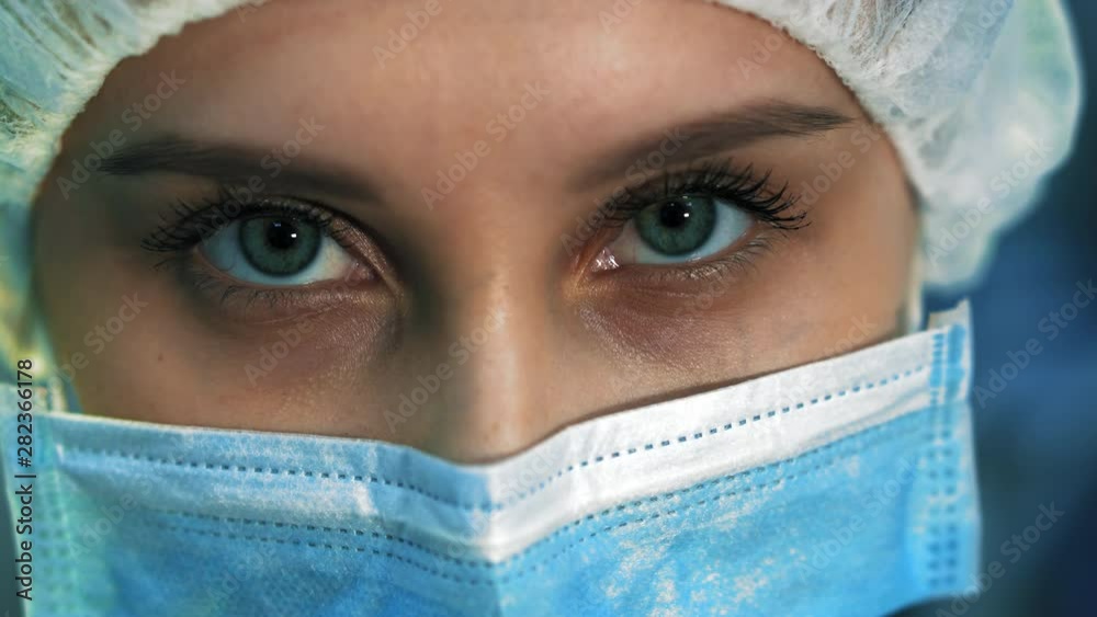 Extra close-up of the eyes tired nurse. She is in a mask looking at the camera, after surgery Extra close-up of the eyes tired nurse. She is in a mask looking at the camera, after surgery