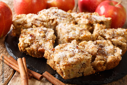 Apple Bars are a perfect Autumn dessert that mixes apple pie and blondies close-up on a slate board. horizontal