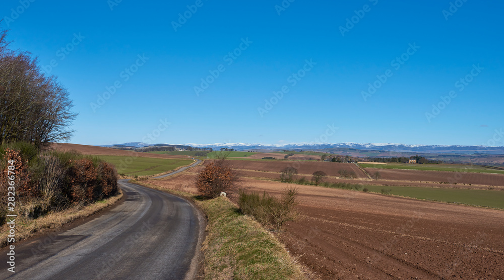 A curving minor road near Letham in Angus, wends its way towards a crossroads with a magnificent view of the snow capped Angus Glens beyond. A curving minor road near Letham in Angus, wends its way towards a crossroads with a magnificent view of the snow capped Angus Glens beyond.