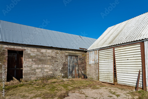 The Corner of a Farm yard with Tin covered Roofed Farm Buildings.