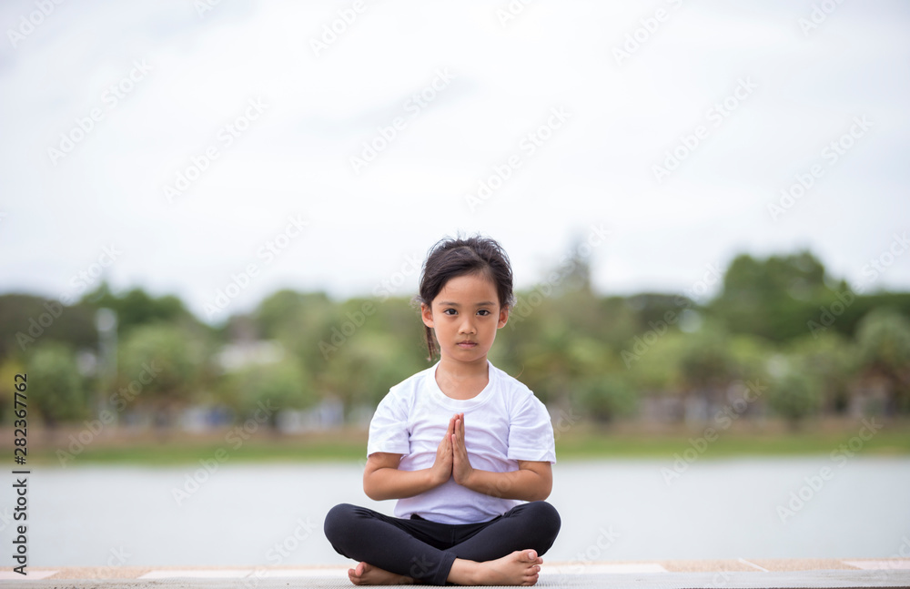 Fototapeta premium beautiful little asian child girl doing yoga in the public park.