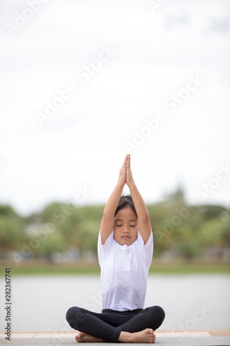beautiful little asian child girl doing yoga in the public park.