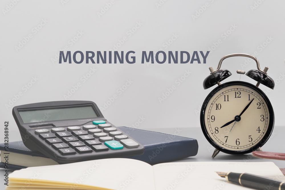 Morning Monday Concept, alarm clock with notebook, calculator and pen on working table Morning Monday Concept, alarm clock with notebook, calculator and pen on working table