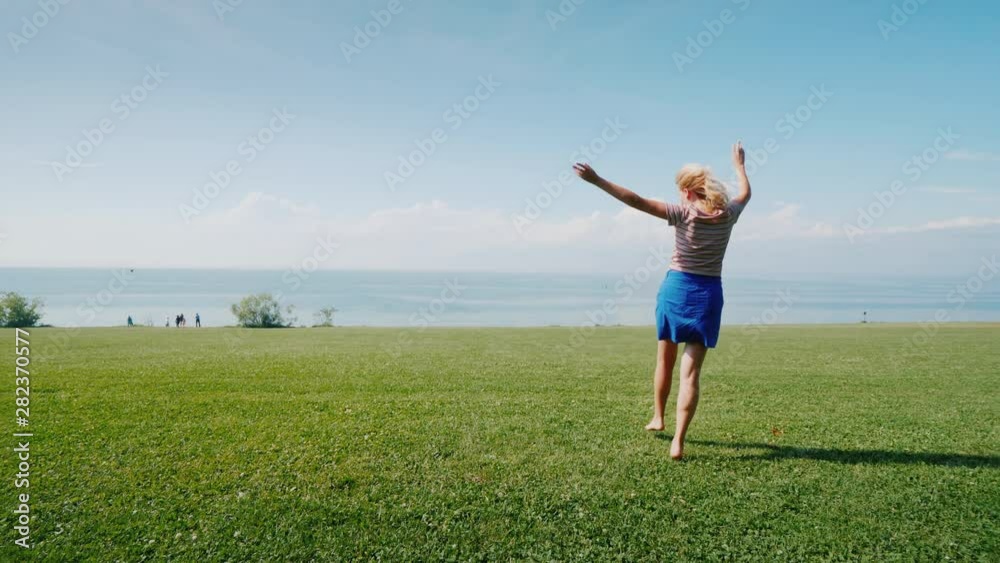Cheerful active woman is walking on a green meadow. Youth and activity Cheerful active woman is walking on a green meadow. Youth and activity