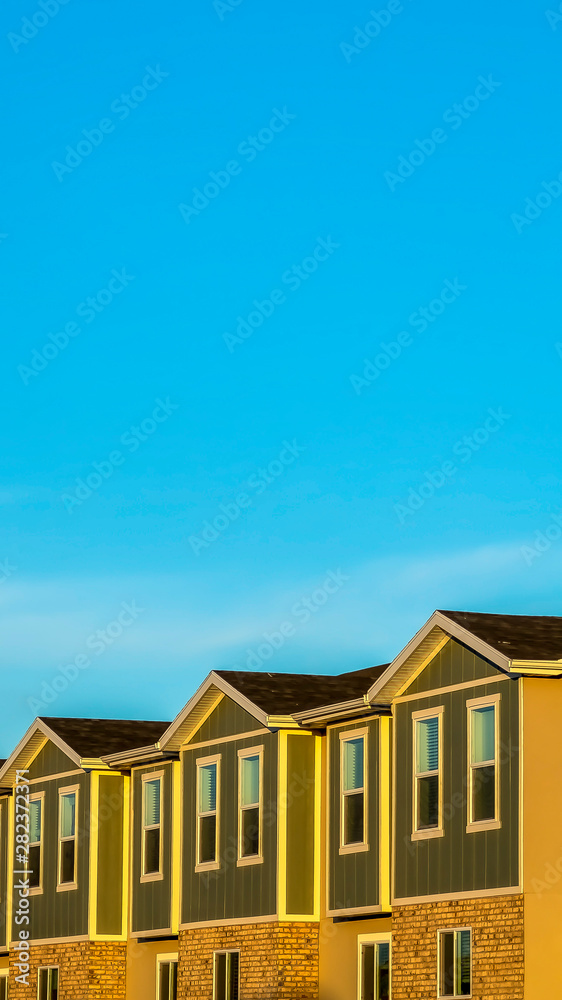 Vertical frame Blue sky over multi storey townhouses with wood brick and concrete exterior wall Vertical frame Blue sky over multi storey townhouses with wood brick and concrete exterior wall
