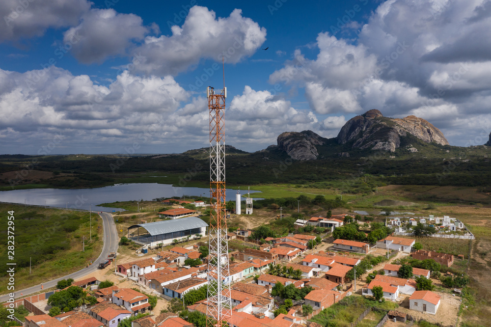 Mobile Antenna in a small city surrounding by small houses and rocks 