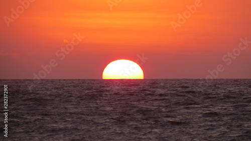 Sol escondiéndose, se oculta en el horizonte del mar © Juan