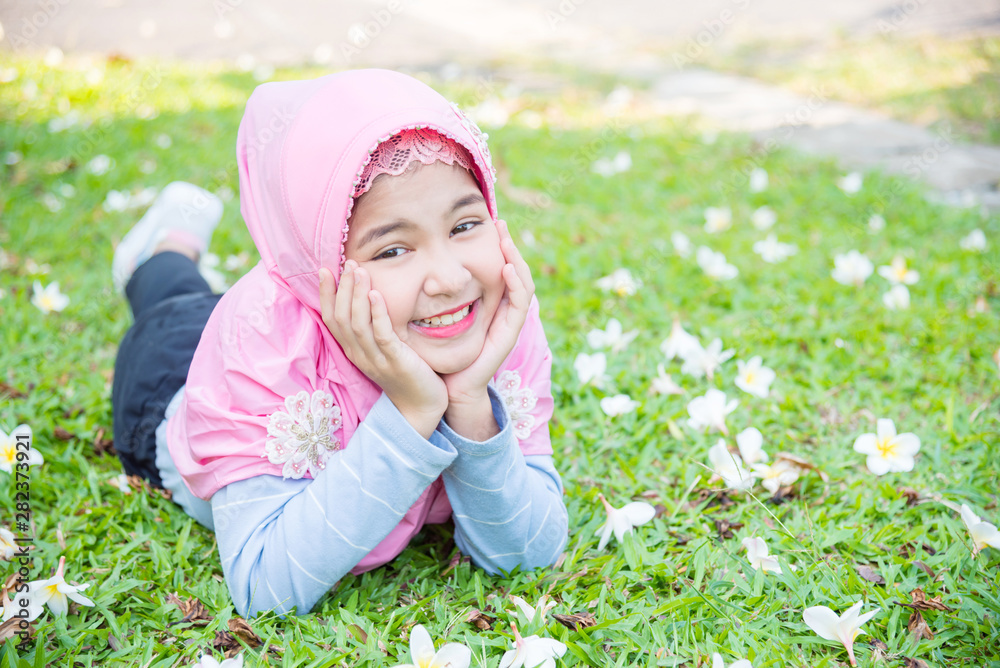 Pretty muslim girl wearing pink color hijab lying on grass and smiles. Pretty muslim girl wearing pink color hijab lying on grass and smiles.