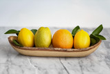 Fresh Common Citrus Fruits on wood plate on white marble table background - Image