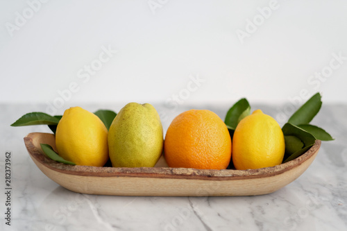 Fresh Common Citrus Fruits on wood plate on white marble table background - Image