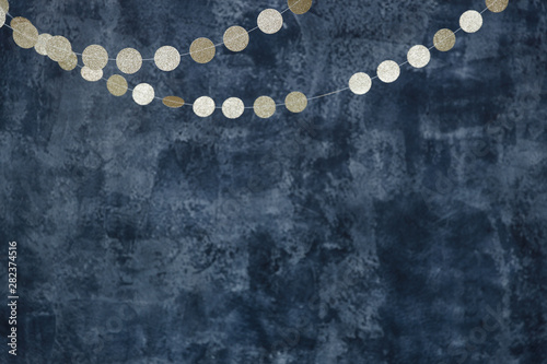 Gold garlands on a smoky dark blue background. Birthday and holiday decor.