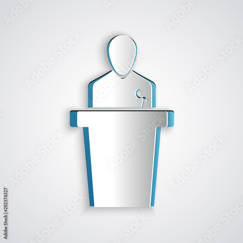 Paper cut Speaker icon isolated on grey background. Orator speaking from tribune. Public speech. Person on podium. Paper art style. Vector Illustration