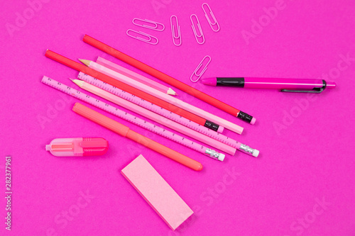 Pink office accessories are lying on rosy background