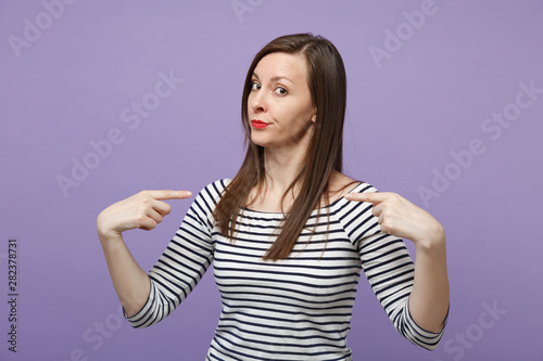Puzzled young brunette woman in casual striped clothes posing isolated on violet purple background studio portrait. People lifestyle concept. Mock up copy space. Pointing index fingers on herself.