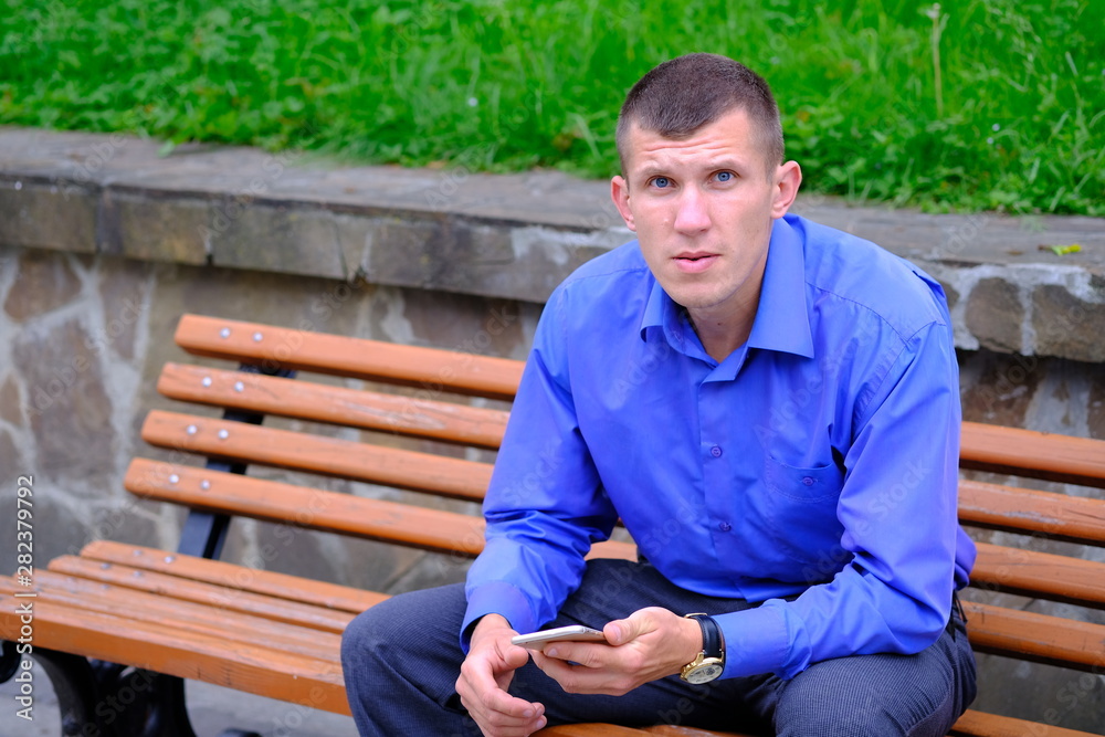 Obraz premium Confident seriously young man holding smartphone. 