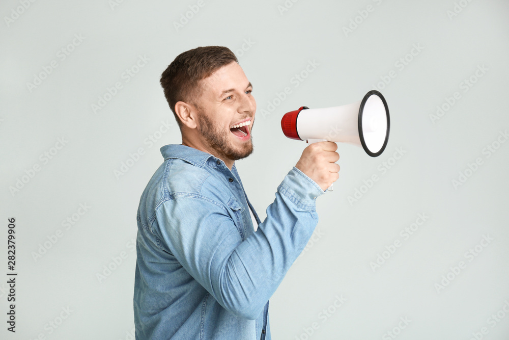 Young man with megaphone on light background Young man with megaphone on light background