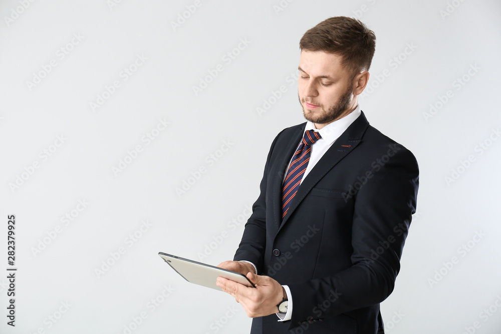 Handsome businessman with tablet computer on light background Handsome businessman with tablet computer on light background