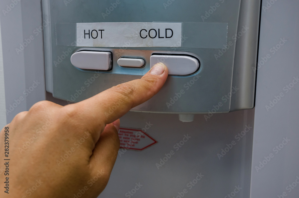 finger presses the cooler's hot water button. Close-up. finger presses the cooler's hot water button. Close-up.
