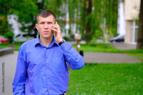 Confident seriously young man holding smartphone. 