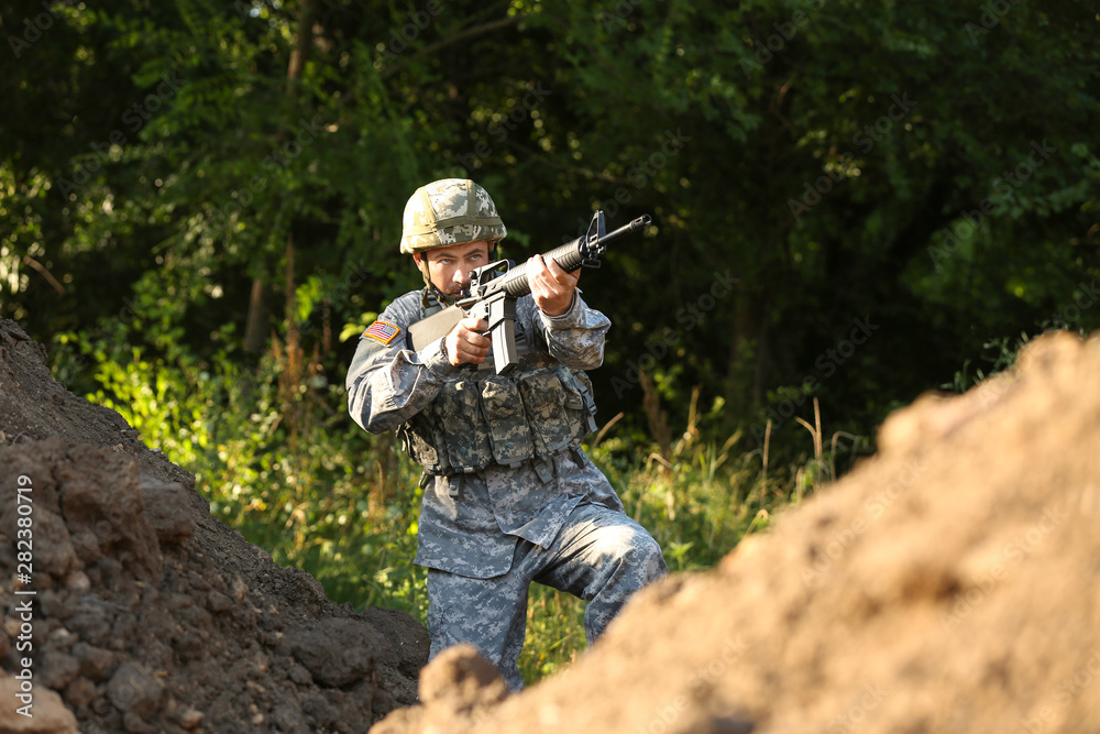 Soldier in camouflage taking aim outdoors Soldier in camouflage taking aim outdoors