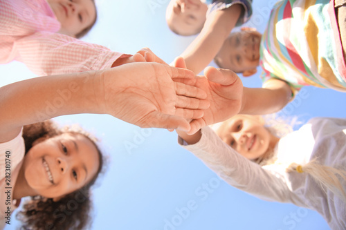 Cute little children putting hands together outdoors, bottom view