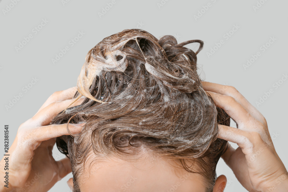Naklejka premium Beautiful young woman washing hair against grey background, closeup