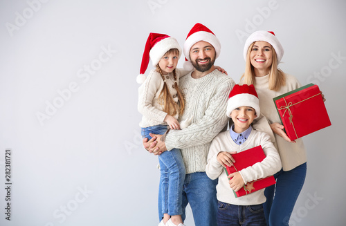 Happy family with Christmas gifts on light background