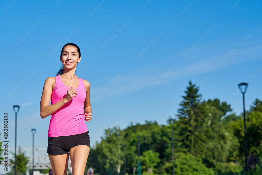Young fitness woman running at forest trail.