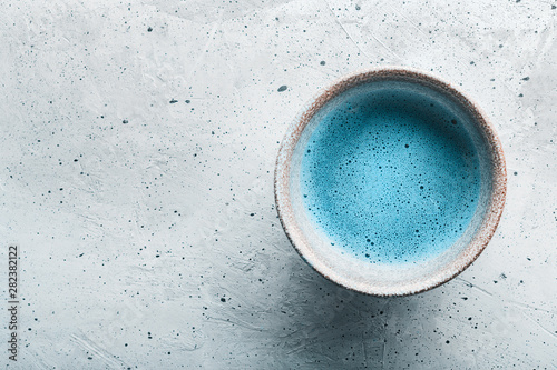 Blue tea matcha in a bowls and chasen on concrete surface with copy space