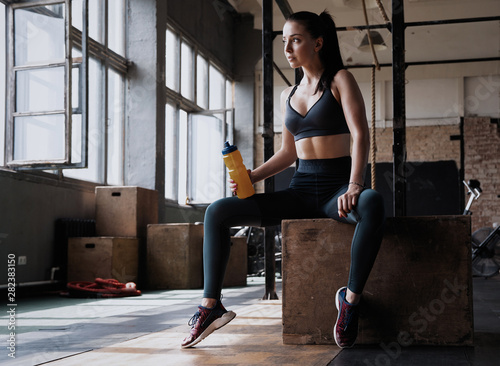 Fitness woman sitting on a box at gym after her workout.