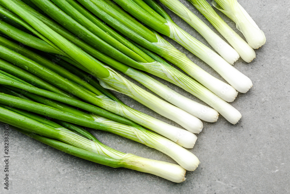 Obraz premium Fresh spring onions with green chive on gray background