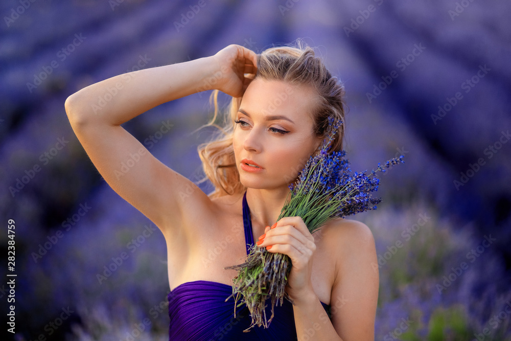 Naklejka premium Beautiful girl on the lavender field. Beautiful woman in the lavender field on sunset.