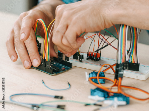 Electronic engineering workplace. Technician connecting components at lab.