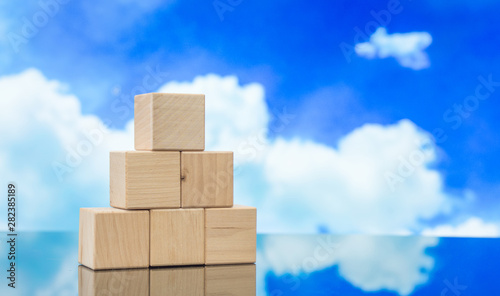 Pyramid of wooden cubes against the blue sky. Wooden cube Stacked in Pyramid shape without graphics for Business and design concept  Symbol of leadership  Teamwork and Growth.