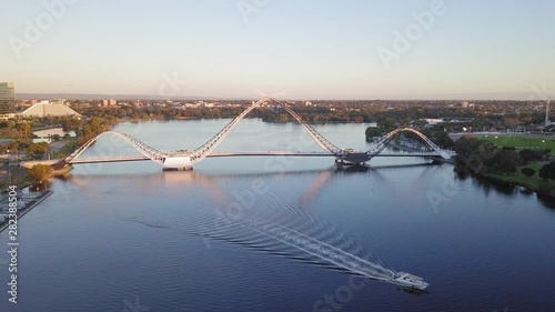 Aerial view of a Matagarup Bridge in Perth, Western Australia with boat going through waves on Swan River. Camera forward motion photo