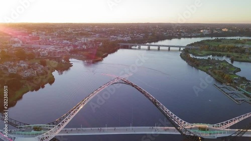 Aerial view of a Swan River with backwards camera motion revealing Matagarup Bridge with people going to the other side. photo