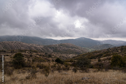 gray-brown slopes on a misty cloudy autumn day, with clouds in the sky. © StockAleksey