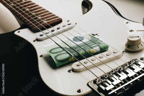 Money under the strings of a guitar. One hundred euros under the strings of a guitar.