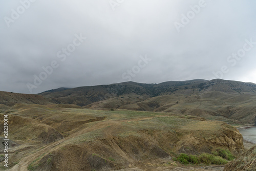 gray-brown slopes on a misty cloudy autumn day, with clouds in the sky.