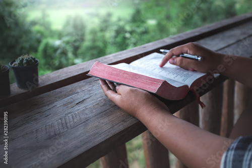 close up hands of man reading and learning a holy bible in morning on wooden table. christian concept.