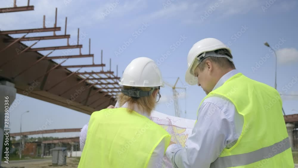 Male and female engineers are discussing a flyover construction project. Developers are working on project documentation at a construction site. Male and female engineers are discussing a flyover construction project. Developers are working on project documentation at a construction site.