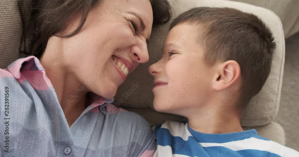 Happy mother and son nuzzling while relaxing on sofa at home Happy mother and son nuzzling while relaxing on sofa at home