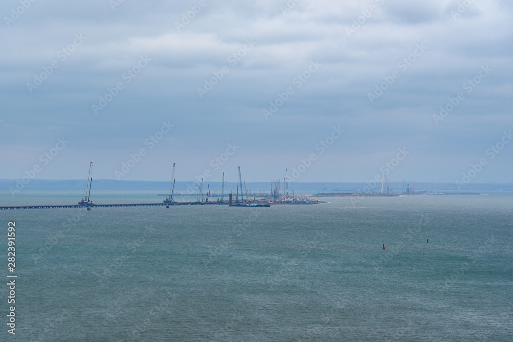 The shore of the Kerch Strait during the construction of the Kerch Bridge in cloudy weather with clouds in the sky. .