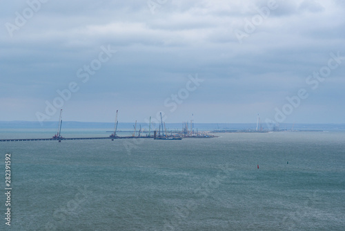 The shore of the Kerch Strait during the construction of the Kerch Bridge in cloudy weather with clouds in the sky. .