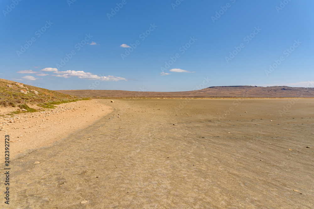 the dried-up bottom of the lake, on a sunny day with clouds on the sky, shot during the season of golden autumn yellow-golden brown.