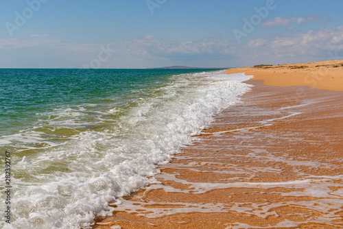 Black Sea coast near the Opuksky nature reserve with bright yellow sand and turquoise water, on a sunny day with clouds on the sky, filmed in the season of golden autumn yellow-golden brown. photo